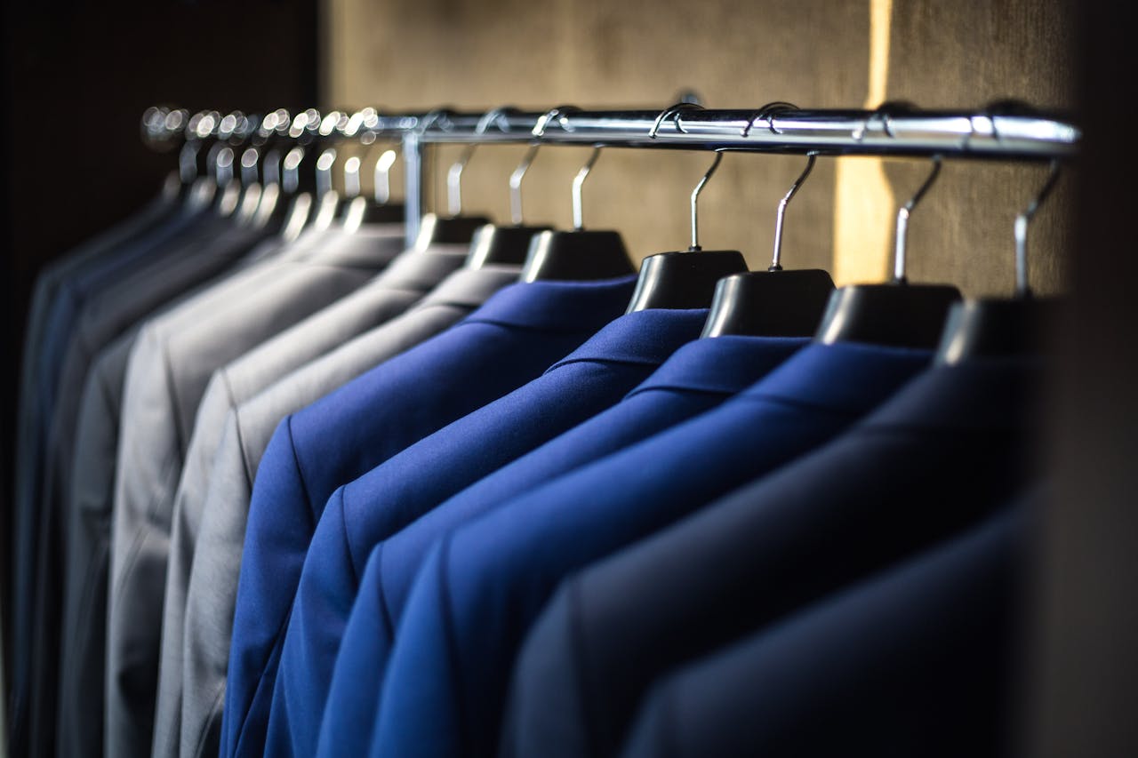 Services Close-up of neatly arranged suits in a wardrobe, showcasing fashion and organization.